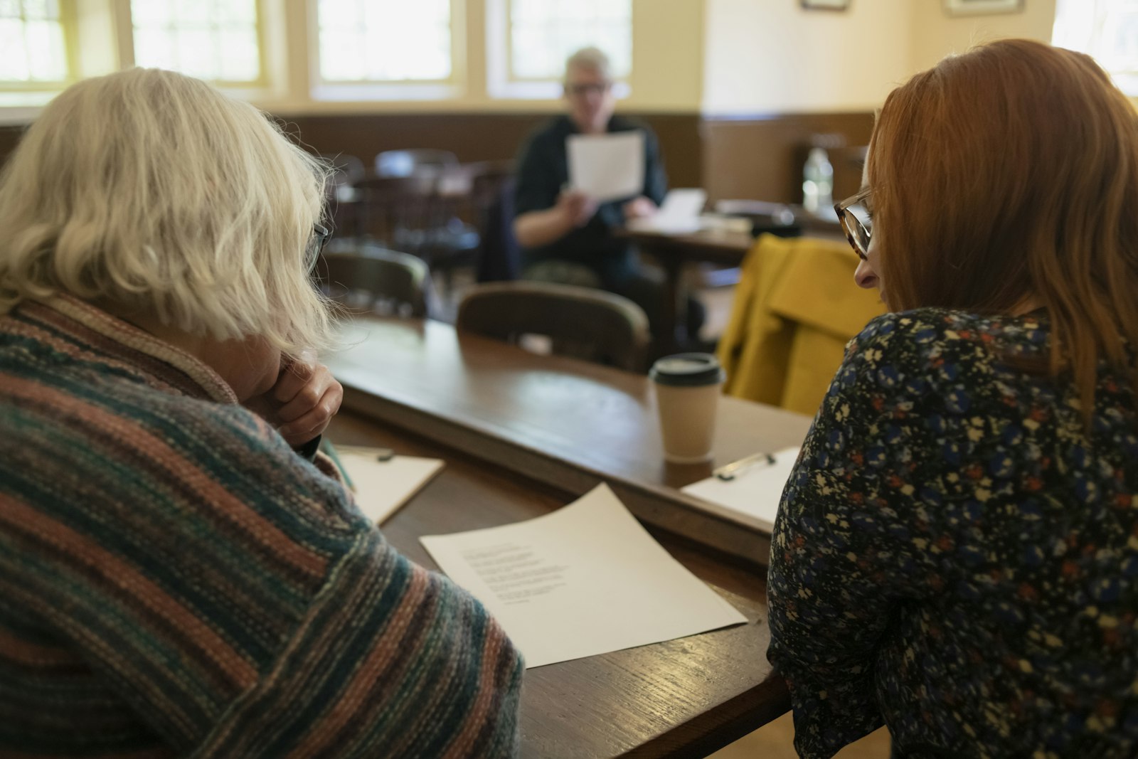 An adult child and parent going through household paperwork together at a table.